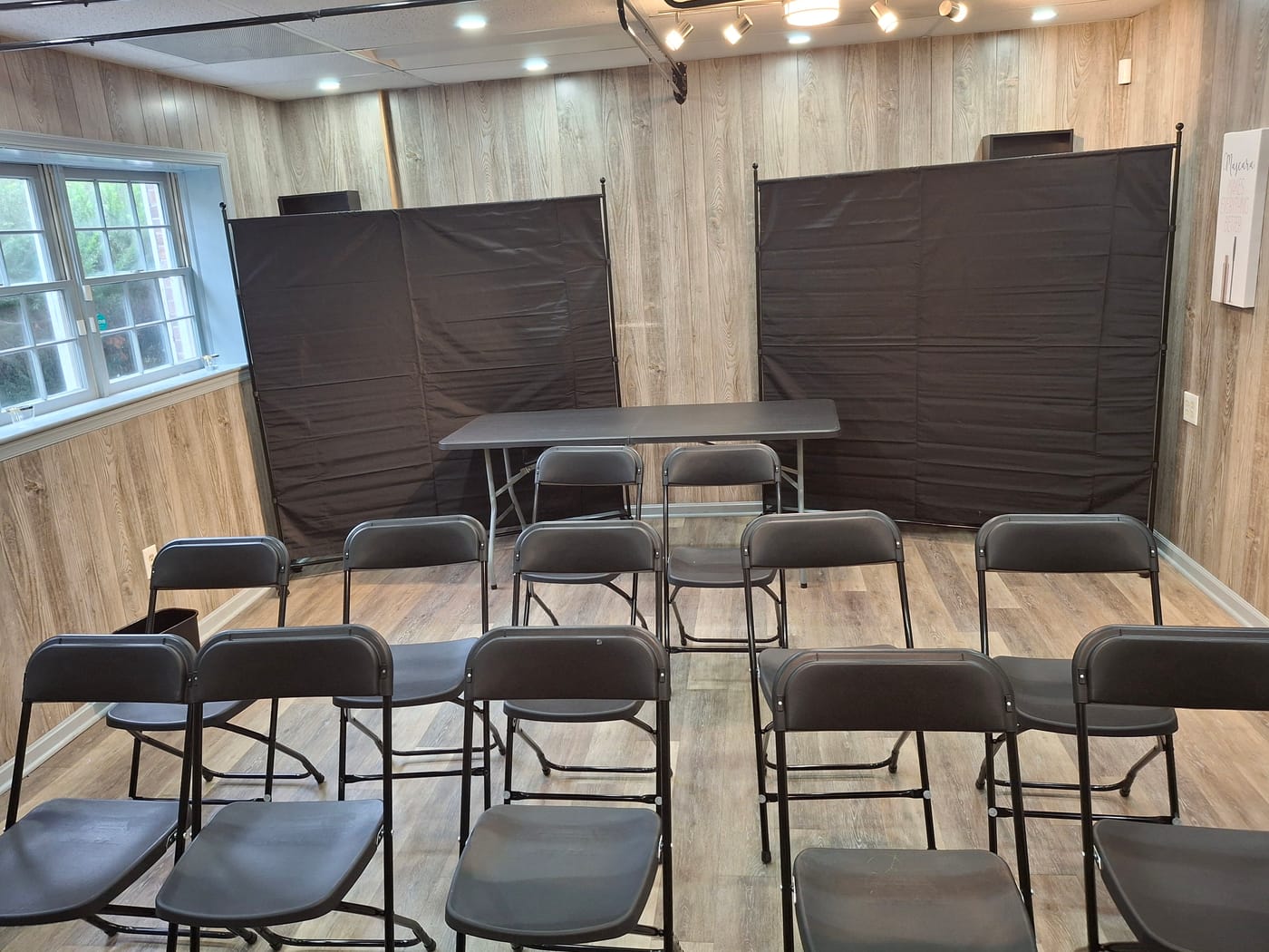 Back salon set up classroom style with rows of folding chairs facing a presenter's table and backdrop